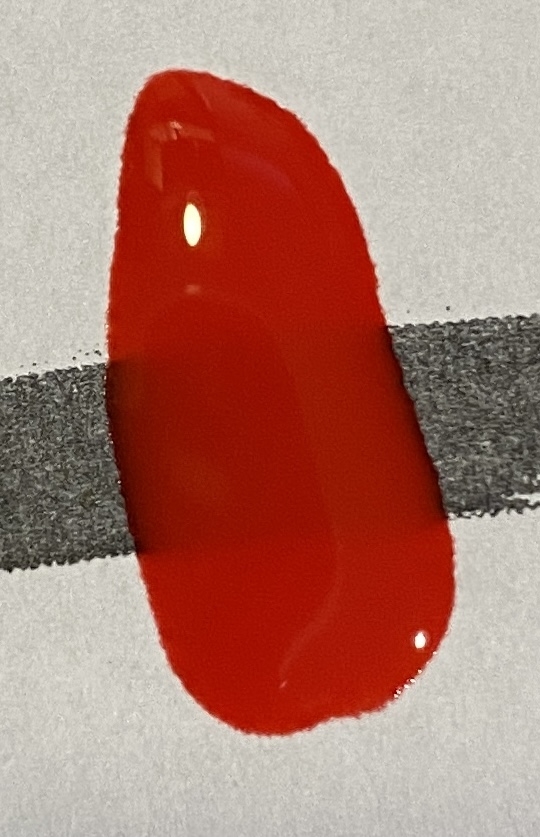 Bilde av fargeprøve tatt i lampelys, hvitt ark med sort tusjstrek som bakgrunn for å vise dekkevne.